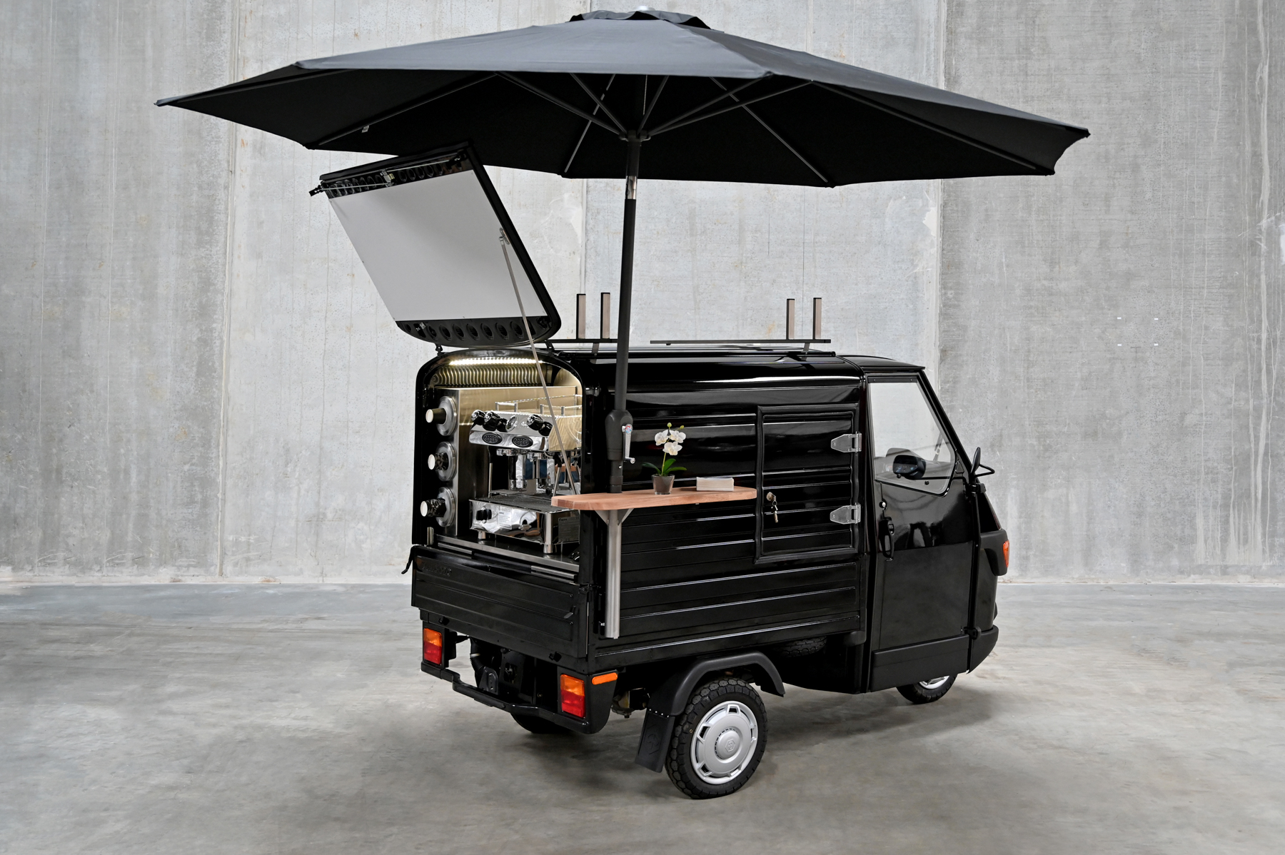 The black Ape coffee van open with umbrella and espresso machine